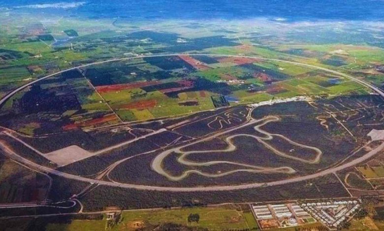 Vista aerea del progetto dell'autodromo NTC-Porsche in Puglia, con una pista principale ovale e percorsi interni complessi, circondati da campi agricoli.