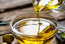 Olio EVO Made in Italy in frantoio con bottiglie etichettate e ulivi sullo sfondo