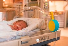 Un neonato prematuro in incubatrice nella Terapia Intensiva Neonatale, con la presenza rassicurante dei genitori.