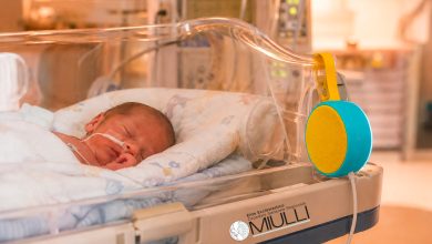 Un neonato prematuro in incubatrice nella Terapia Intensiva Neonatale, con la presenza rassicurante dei genitori.