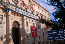 Immagine satirica del Palazzo Ducale di Martina Franca con la scritta Benvenuti a Locorotondo, stendardi della Festa dell'Unità e cartelli per Locorotondo e Capitolo