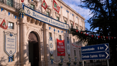Immagine satirica del Palazzo Ducale di Martina Franca con la scritta Benvenuti a Locorotondo, stendardi della Festa dell'Unità e cartelli per Locorotondo e Capitolo